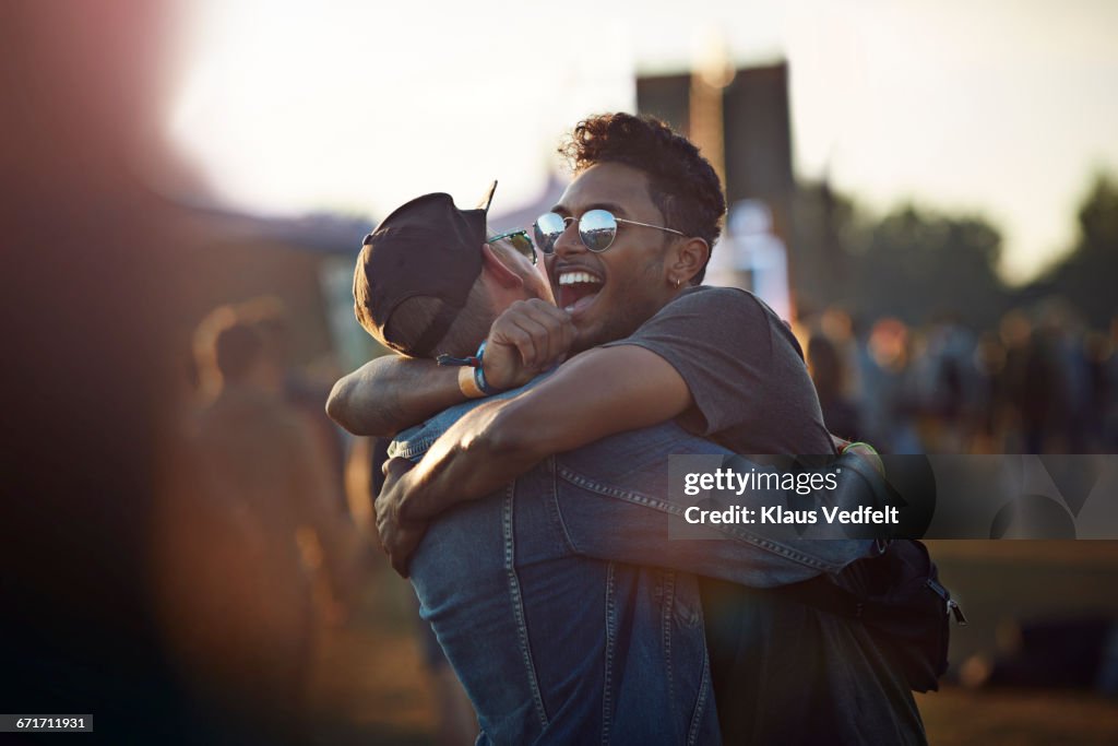 Friends hugging & laughing at big festival