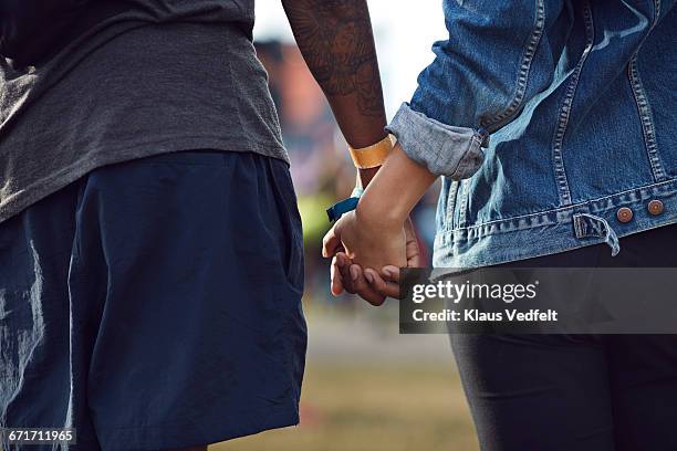 close-up of couple holding hands at festival - couple concert photos et images de collection