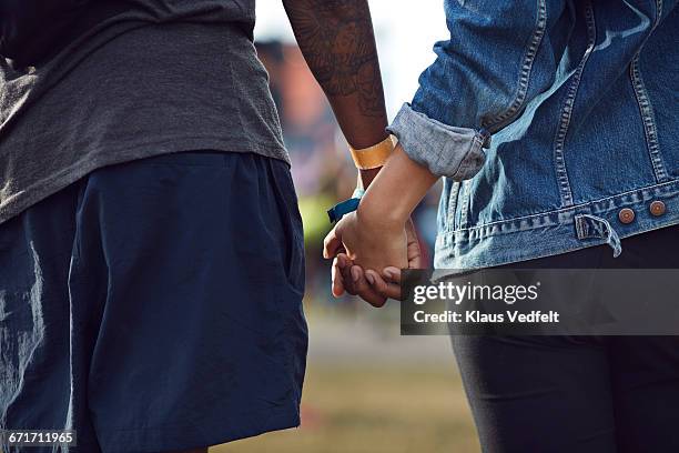 close-up of couple holding hands at festival - holding hands stock pictures, royalty-free photos & images