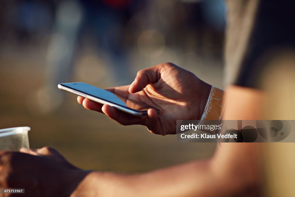 Close-up of hand scrolling on phone at festival