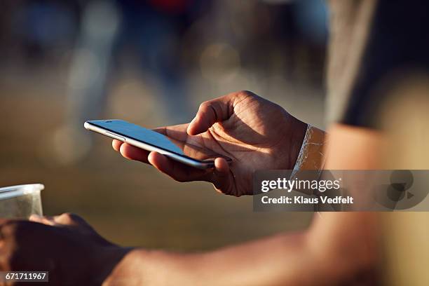 close-up of hand scrolling on phone at festival - man holding phone imagens e fotografias de stock