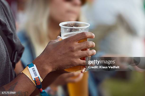 close-up uf hands holding beer, at festival - bracelet stockfoto's en -beelden