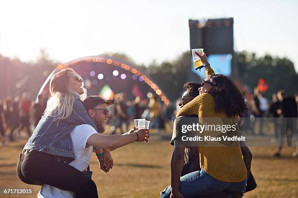 two couples piggybacking at big festival outside - couple concert stock pictures, royalty-free photos & images