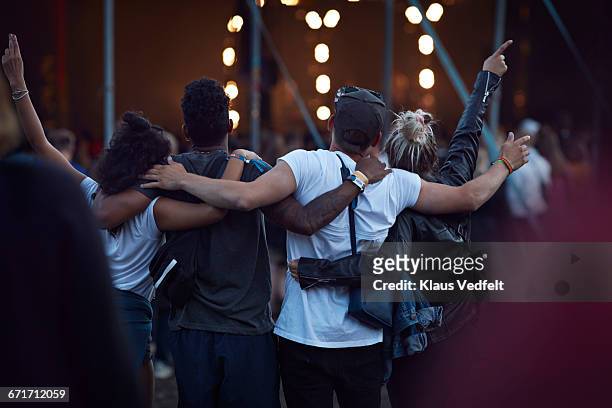 friends with arms around each other at concert - concierto fotografías e imágenes de stock