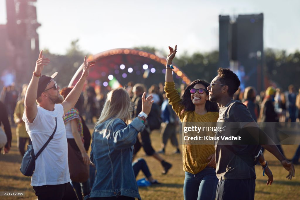 Friends dancing at festival with arms in air