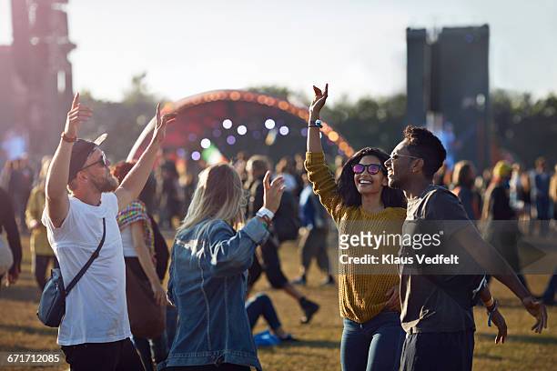 friends dancing at festival with arms in air - music festival stock pictures, royalty-free photos & images