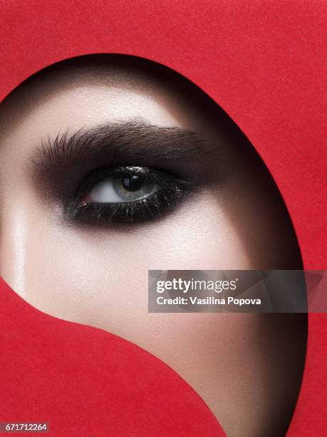 beautiful woman looking through paper - black eyeshadow stock pictures, royalty-free photos & images