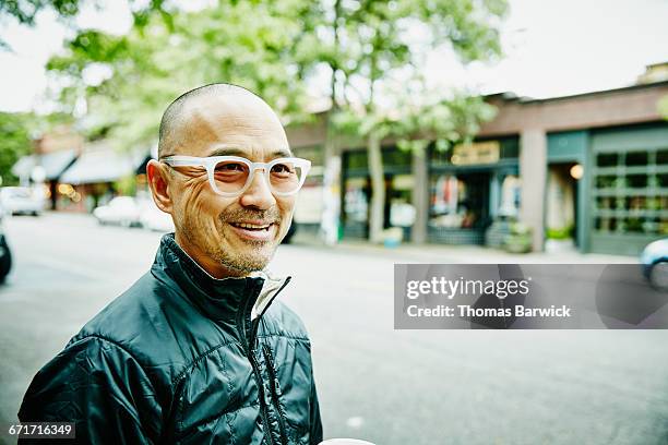 smiling man running errands in neighborhood - koreanischer abstammung stock-fotos und bilder