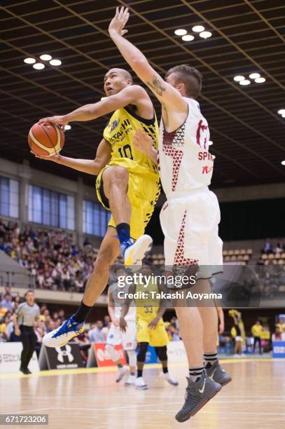 Aki Chambers of the SunRockers tries to shoot under pressure from Ryan Spangler of the Kawasaki Brave Thunders during the B. League match between...