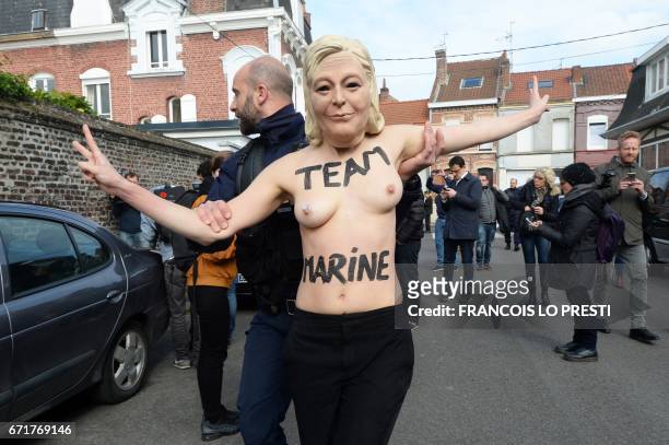 Member of feminist activist group Femen is detained by a police officer as they protest against French presidential election candidate for the...