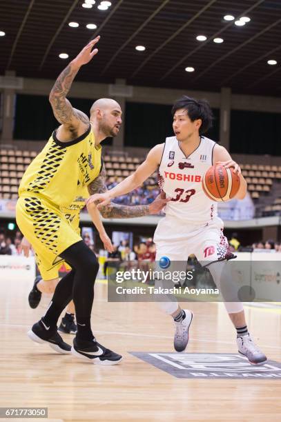 Takumi Hasegawa of the Kawasaki Brave Thunders handles the ball under pressure from Robert Sacre of the SunRockers during the B. League match between...