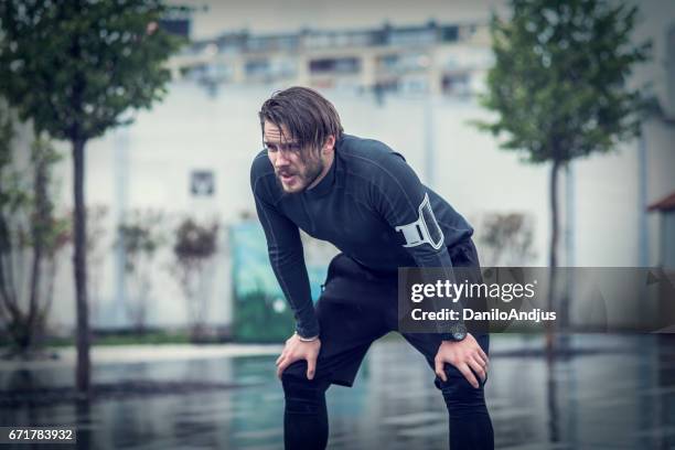 handsome fit man taking a break after workout in the rain - runner tired stock pictures, royalty-free photos & images