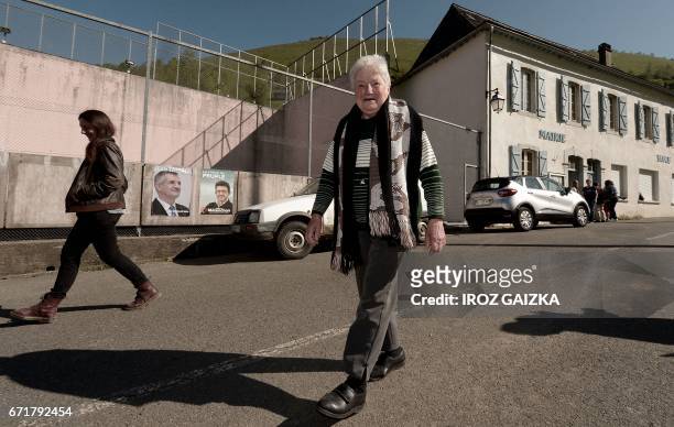 Voters walk past election campaign posters for French lawmaker and independent candidate for Jean Lassalle and candidate for the far-left coalition...