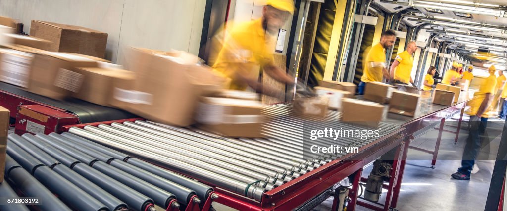 Postal workers inspecting packages on a conveyor belt