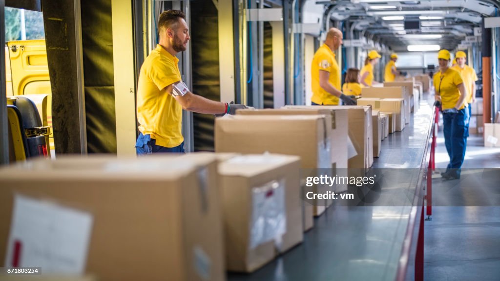 Delivery warehouse workers handling packages on conveyor belt