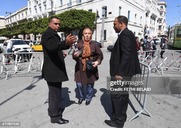 Tunisian security check the ID of a French national woman residing in Tunisia as she arrives at the French embassy in Tunis to cast her vote for the...