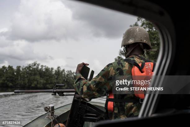 Member of NNS Pathfinder of the Nigerian Navy forces surveys his surroundings from the back of a gunboat patrolling in the creeks to look for illegal...