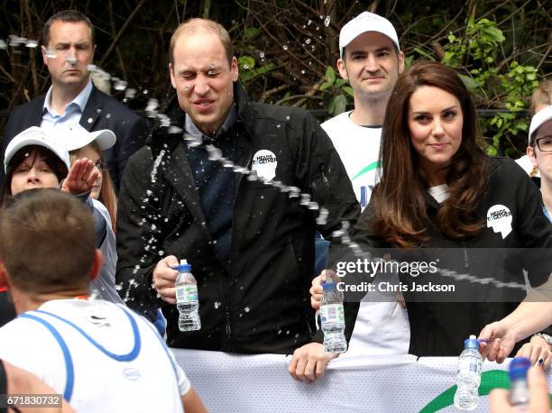 Runner squirts water towards Prince William, Duke of Cambridge and Catherine, Duchess of Cambridge as they hand out water to runners during the 2017...