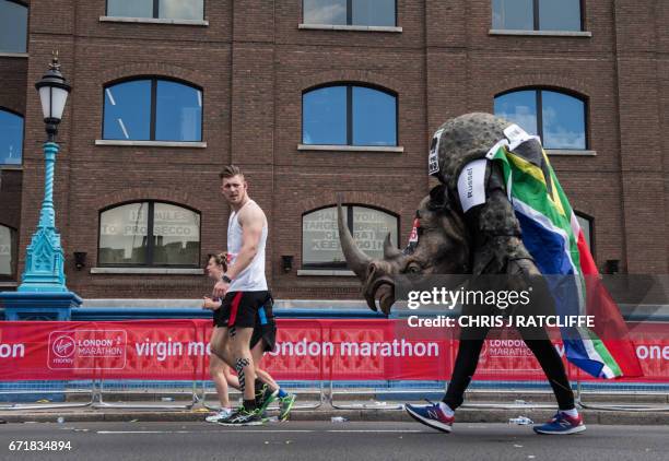 Runner dressed as a rhino crosses the half way point past a sign in a window reading '13 miles to prosecco' , on Tower Bridge during the London...