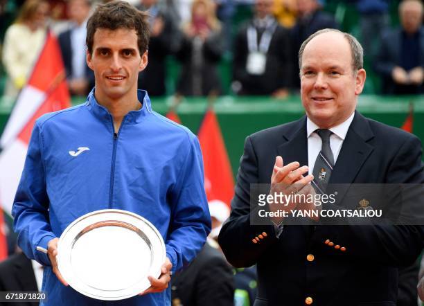 Second-placed Spain's tennis player Albert Ramos-Vinolas holds his trophy as Prince Albert II of Monaco stands by him applauding during the prize...