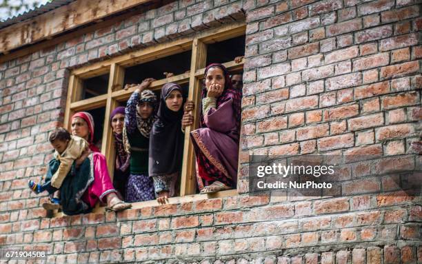 Kashmiri Muslim women look towards the body being carried by the men, of Younis Maqbool Ganie, a pro Kashmir rebel killed in a gun battle with Indian...