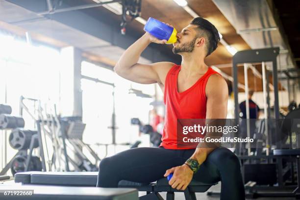 young muscular man drinking a protein drink - protein drink stock pictures, royalty-free photos & images