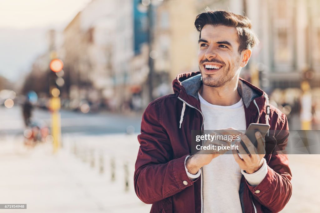 Junger Mann mit Smartphone in der Stadt