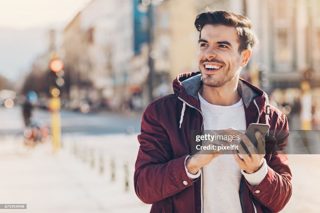 街でスマート フォンを持つ若者