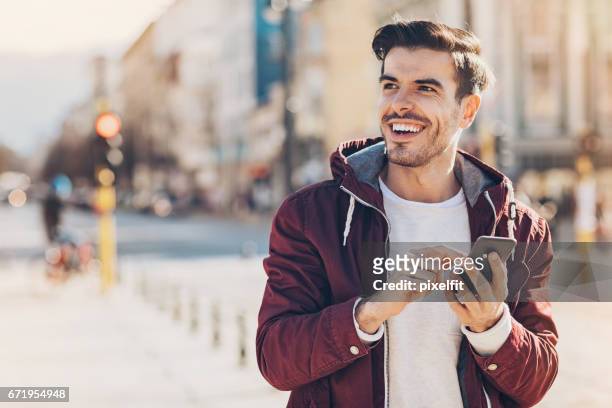 jonge man met slimme telefoon in de stad - alleen één jonge man stockfoto's en -beelden