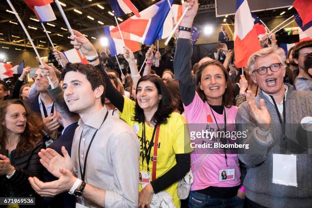 Attendees wave French national flags while reacting to results for the first round of the French presidential election are projected at an En Marche...