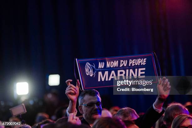 An attendee holds a campaign banner as results for the first round of the French presidential election are projected at a National Front party in...