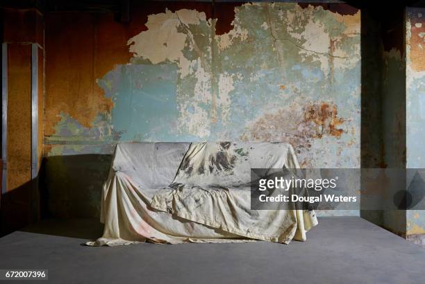sofa covered with dust sheet in decaying room. - protective sheet stock pictures, royalty-free photos & images