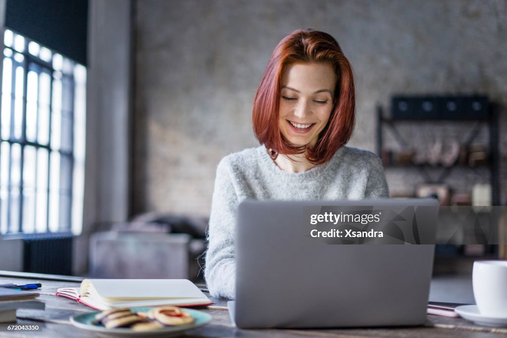 Young woman working on a laptop in a loft