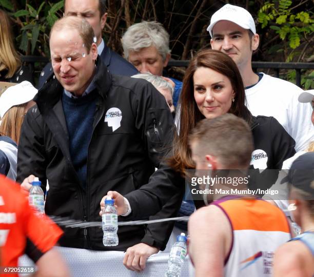 Prince William, Duke of Cambridge is squirted with water as he & Catherine, Duchess of Cambridge hand out water to runners taking part in the 2017...