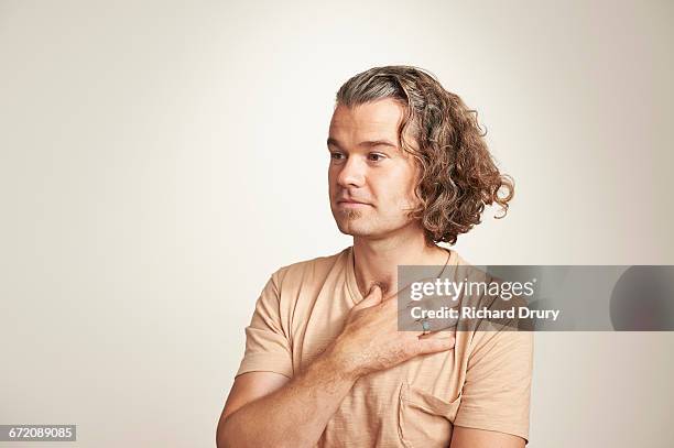 portrait of young man with hand on heart - manos sobre el pecho fotografías e imágenes de stock