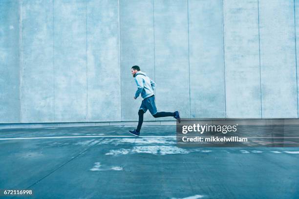 fast runner makes his way past a big grey concrete wall - winter running stock pictures, royalty-free photos & images