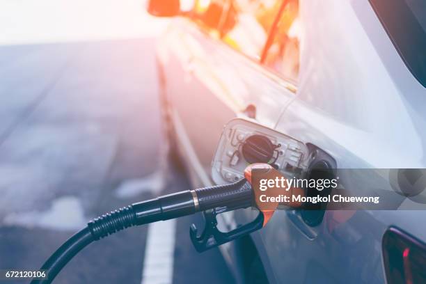 gas nozzle pumping gas into a gray blonde car - gas station ストックフォトと画像