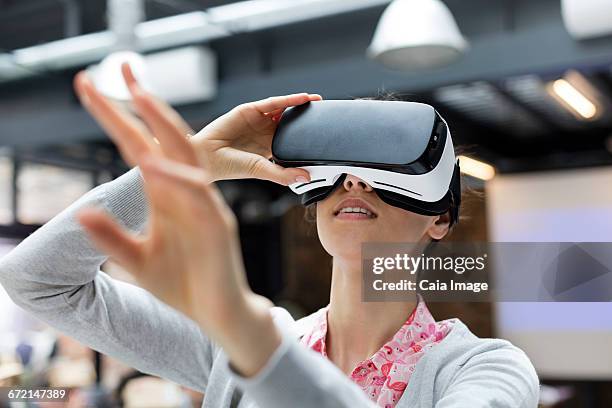 woman trying virtual reality simulator glasses glasses reaching - virtualitytrend stock-fotos und bilder