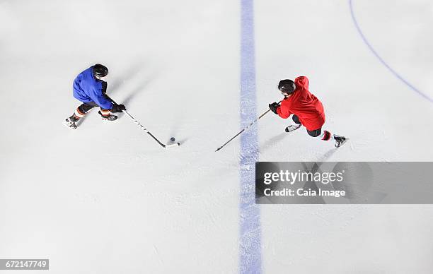 overhead view hockey players going for puck on ice - difensore hockey su ghiaccio foto e immagini stock