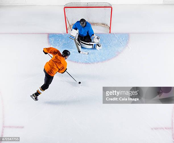 hockey player shooting the puck at goal net - hockey puck top view stock pictures, royalty-free photos & images