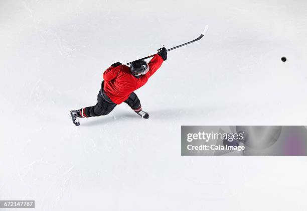 hockey player in red uniform shooting puck on ice - ice rink overhead stock pictures, royalty-free photos & images