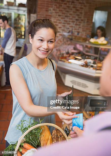 smiling woman paying with credit card at grocery store checkout - debit cards credit cards accepted stock pictures, royalty-free photos & images