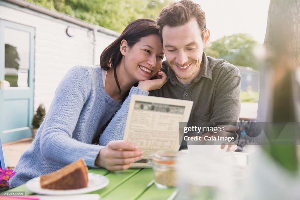 Smiling couple looking at menu at outdoor cafe