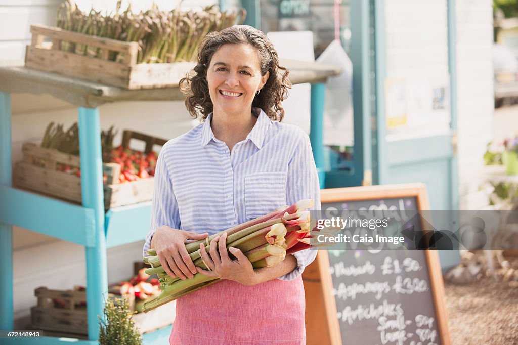 Portrait smiling farmers market worker holding fresh rhubarb