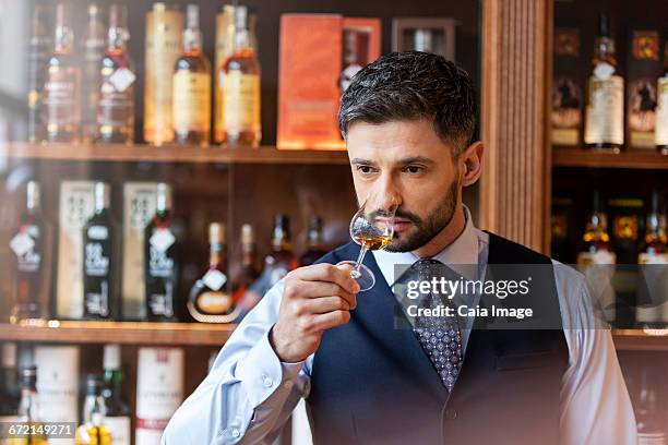 well-dressed man whiskey tasting - whiskey tasting stock pictures, royalty-free photos & images