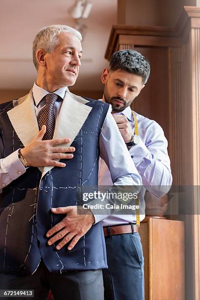 tailor fitting businessman for suit in menswear shop - fashion store staff foto e immagini stock