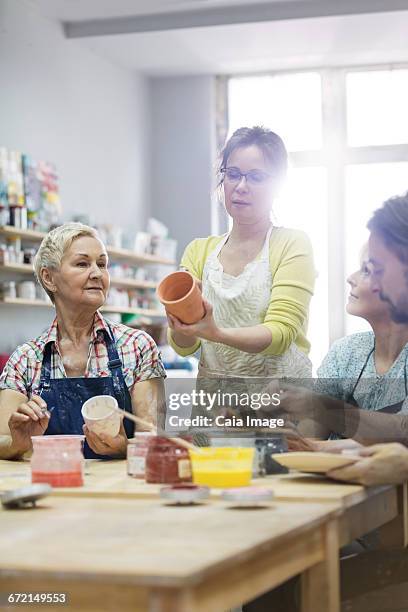 teacher guiding mature students painting pottery in studio - glazen pot stock pictures, royalty-free photos & images