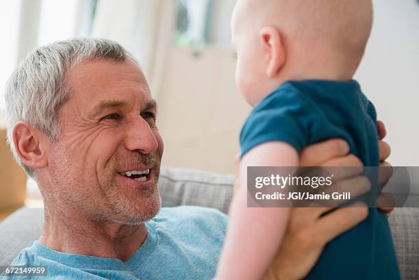 caucasian grandfather holding grandson face to face - grandfather face stock pictures, royalty-free photos & images