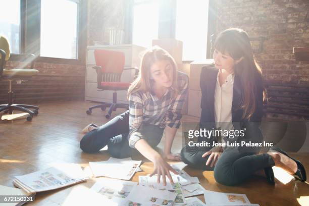 businesswomen discussing paperwork on floor of new office - asia ray stock-fotos und bilder