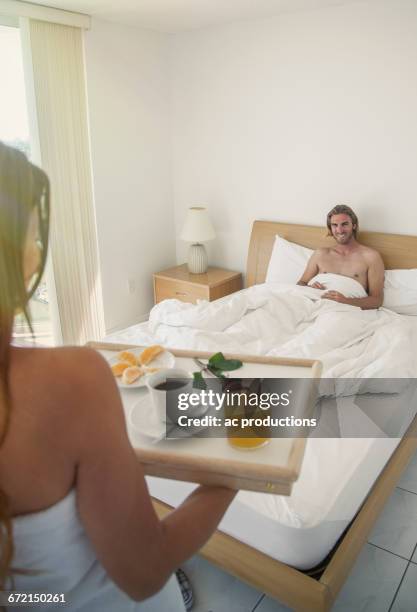 caucasian woman serving man breakfast in bed - breakfast in bed tray stock-fotos und bilder